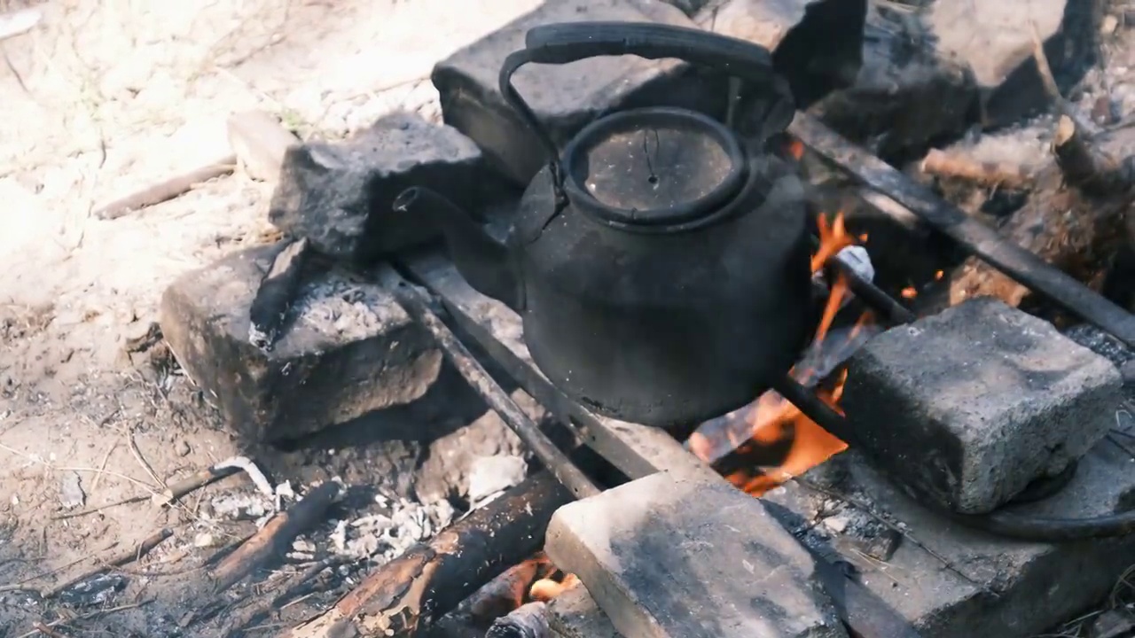 旅游水壶站在一个自制的篝火炉在旅游营地的自然视频素材