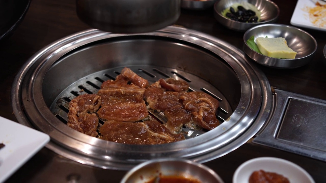 韩国菜，韩式烧烤。韩国烤肉，韩国传统烤肉。把肉切成方块放在烤架上，配上泡菜和米饭视频下载