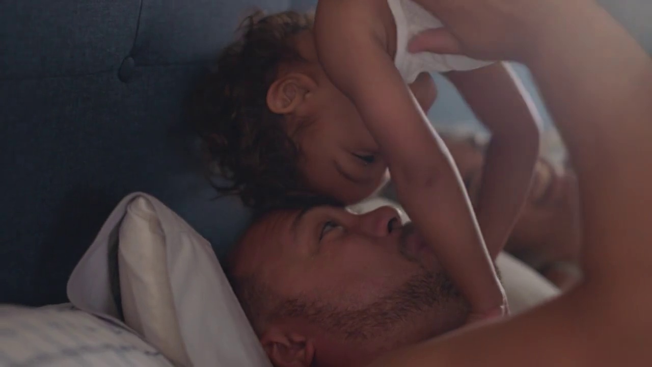 父亲抱起躺在床上的女儿，把她放在自己面前视频素材