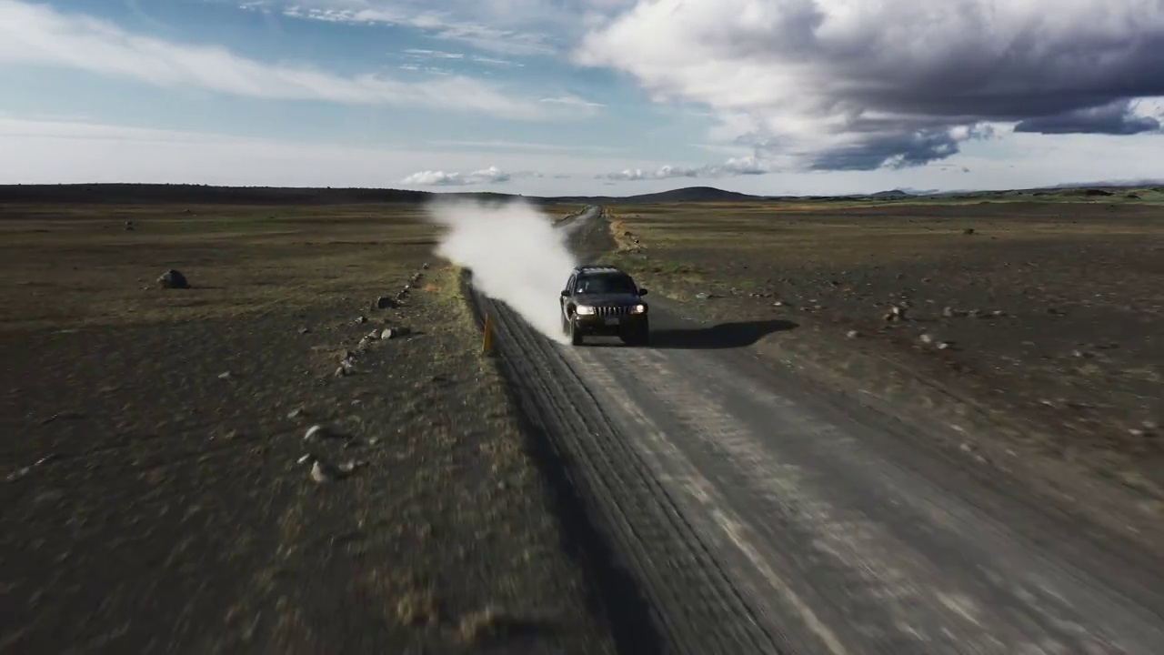 低角无人机拍摄的照片显示一辆4x4在冰岛的一条土路上高速行驶视频下载