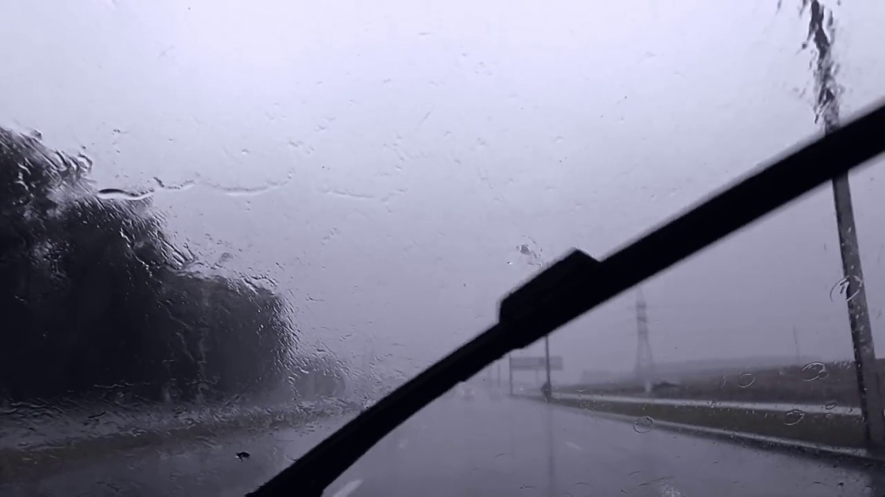 缓慢的运动。在阴雨天行驶的道路上，雨点冲刷着汽车的雨刷视频下载