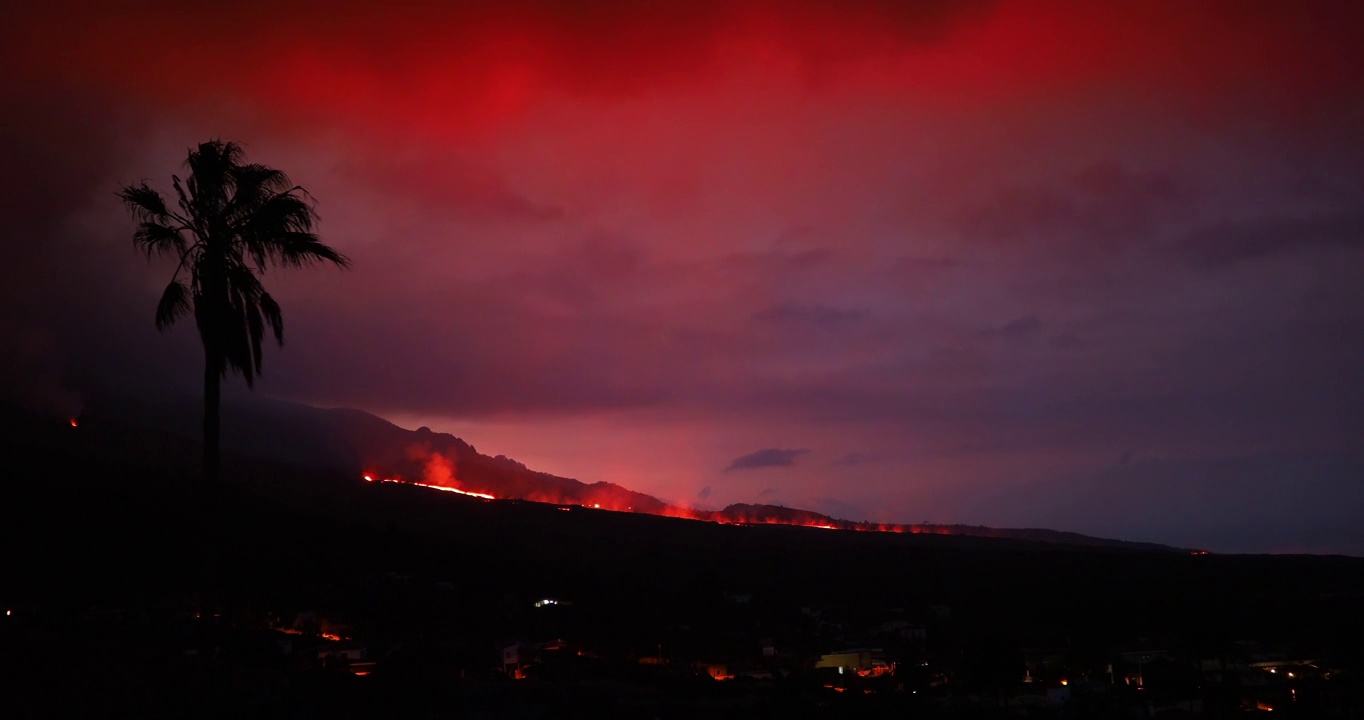 夜晚火山喷发时形成的熔岩河。在塔juya镇的房屋旁边，可以看到一股烟雾和熔岩柱。视频下载