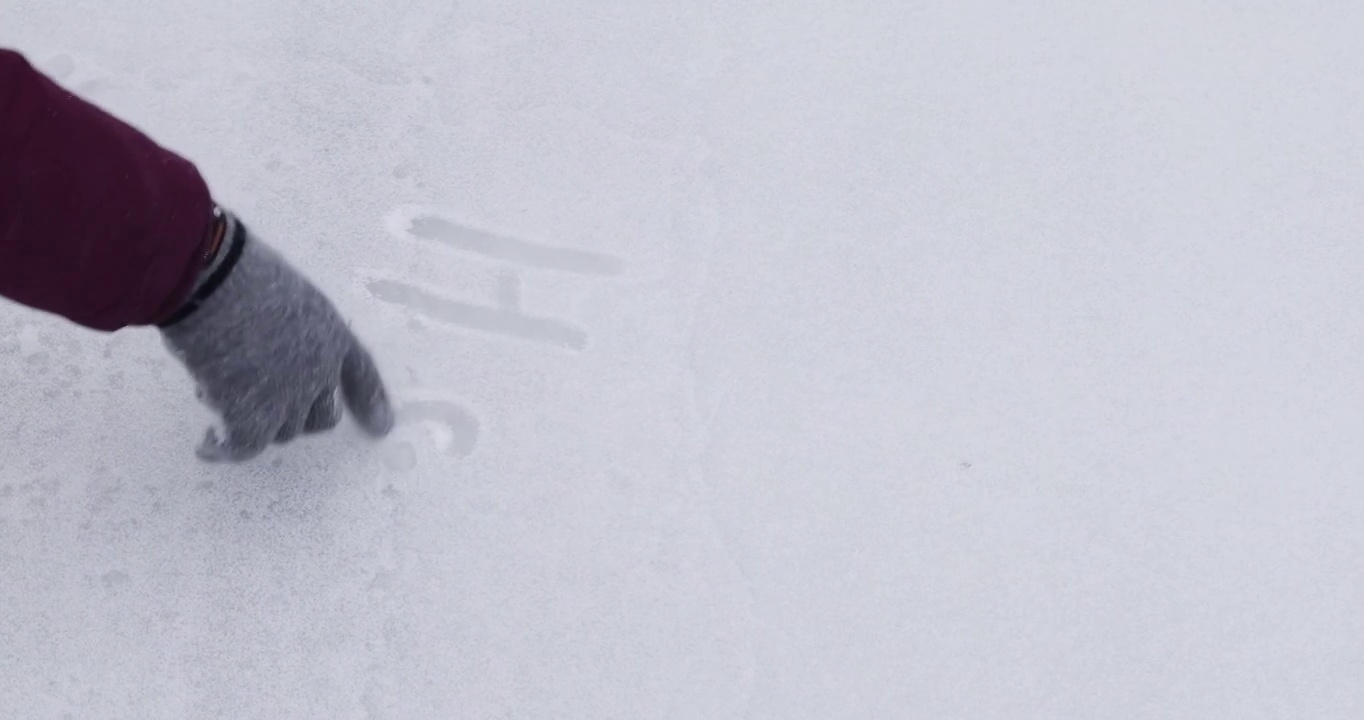快乐的女孩在手套上写冰，洒着雪的题词新年快乐，水平视频下载