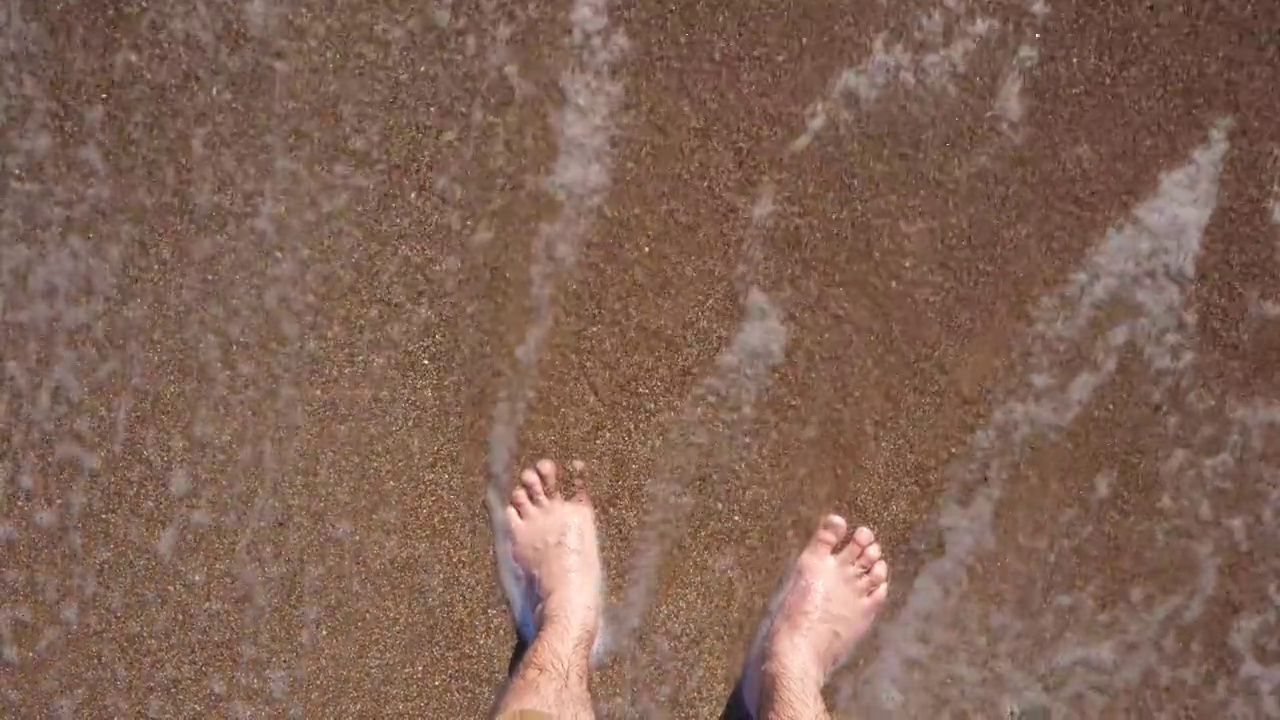 慢动作:双脚踏着波浪在沙滩上视频下载