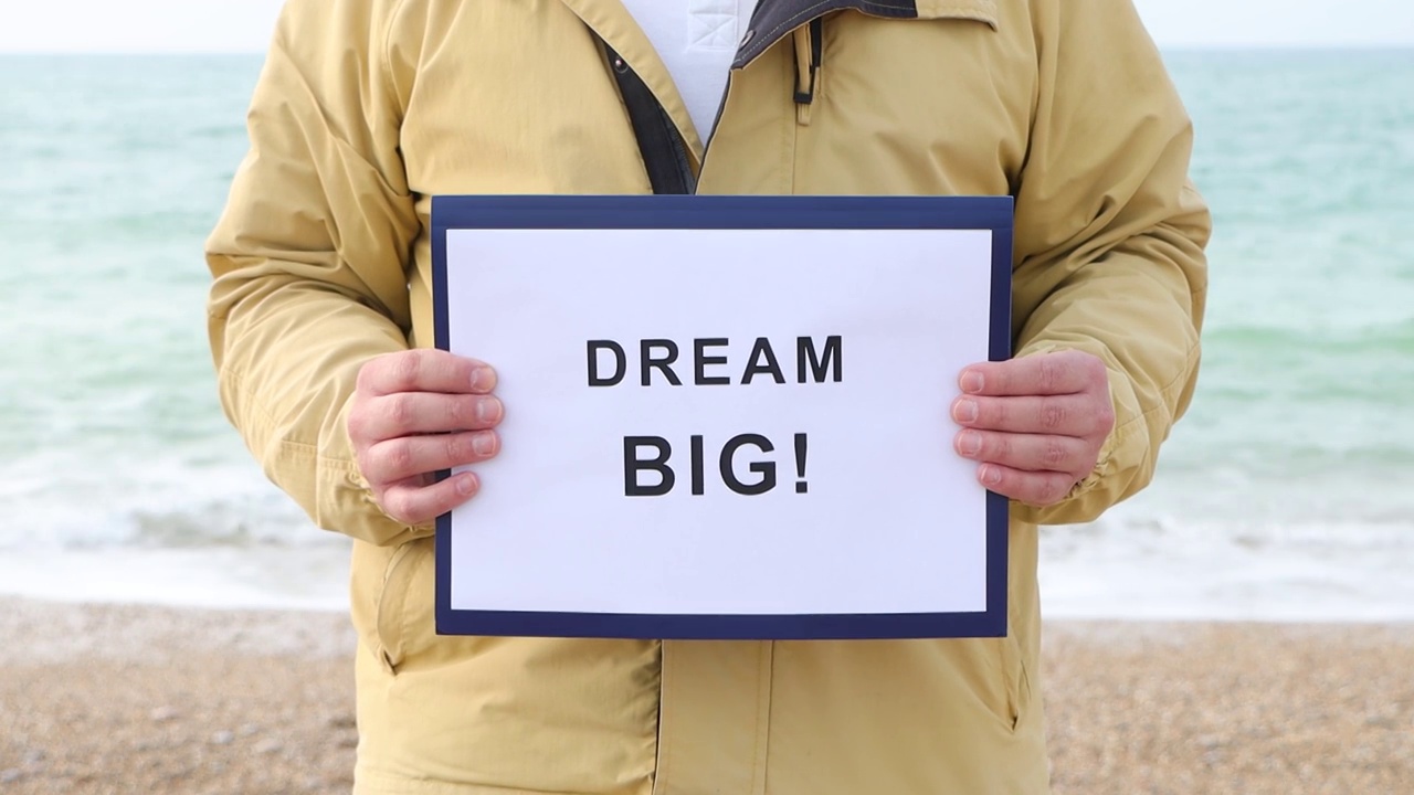 一名男子手持海报，上面写着“梦想远大!”动机概念镜头。视频素材