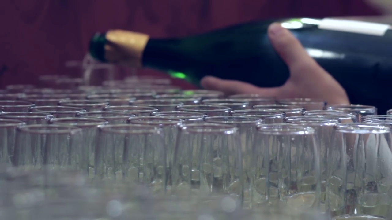 酒吧招待员把香槟倒进放在门边桌子上的玻璃杯里视频下载