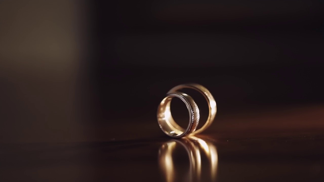 旋转特写旋转婚礼戒指的新郎和新娘在桌子上，婚姻的象征视频素材