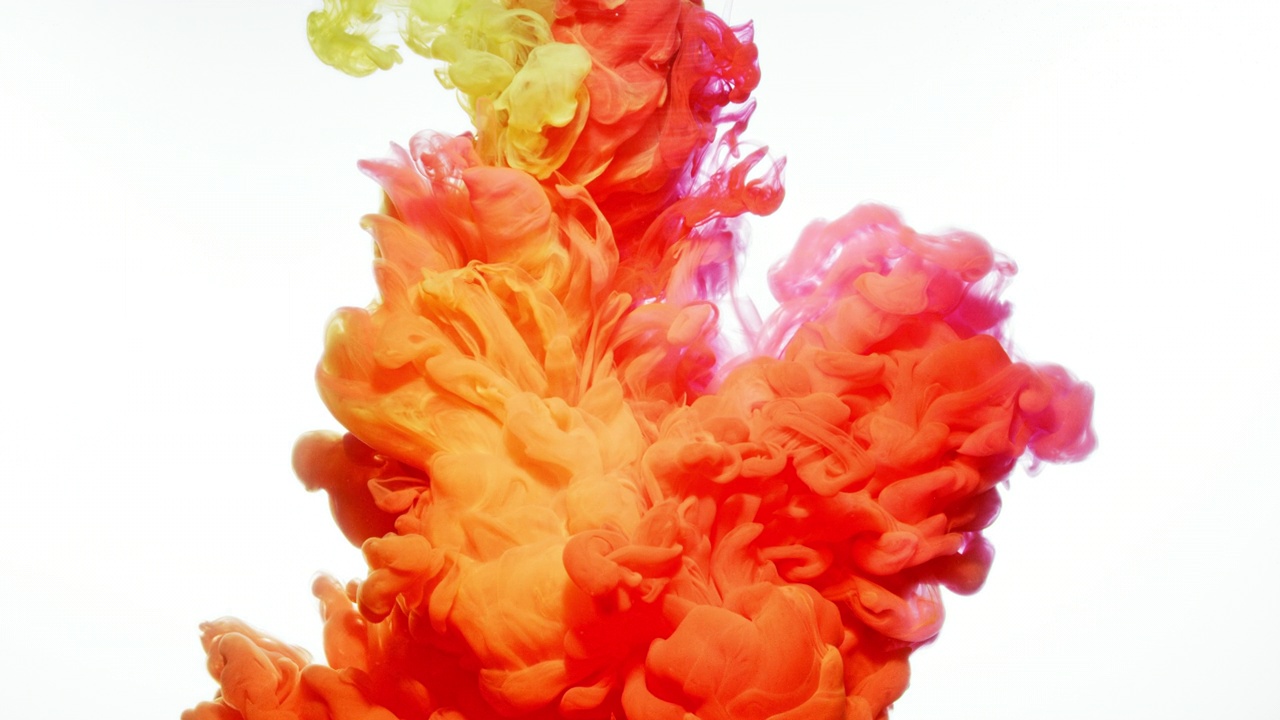 近距离和慢动作的橙色，粉色和黄色的墨水飞溅和相互作用的水，并蔓延到整个框架上的白色背景视频素材
