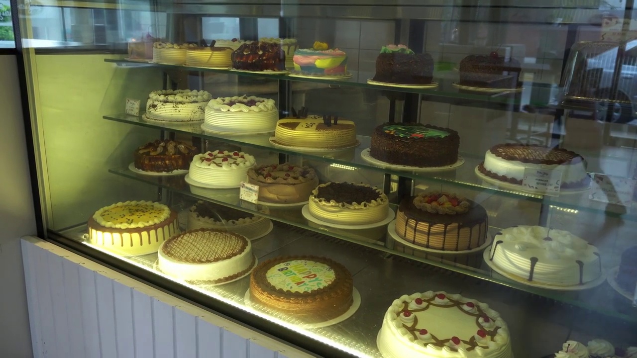在一家意大利面店的玻璃柜台上摆放着各种各样的蛋糕和生日蛋糕视频下载