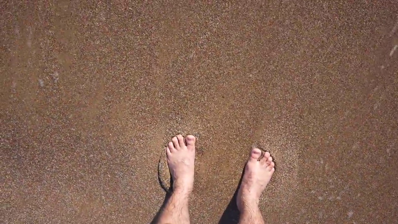 沙滩上踏着波浪的双脚视频下载