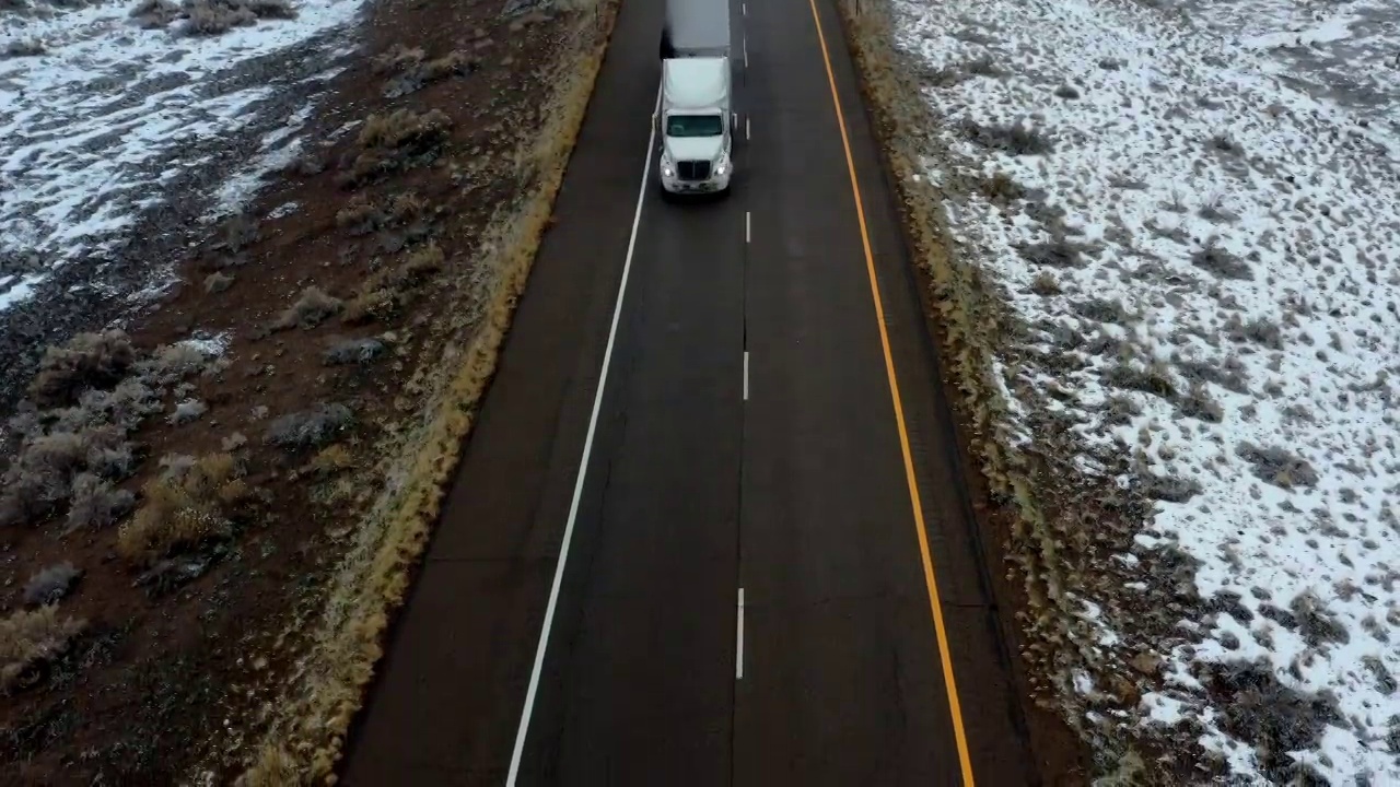 航运业货运卡车在冬季公路无人机跟随视频下载