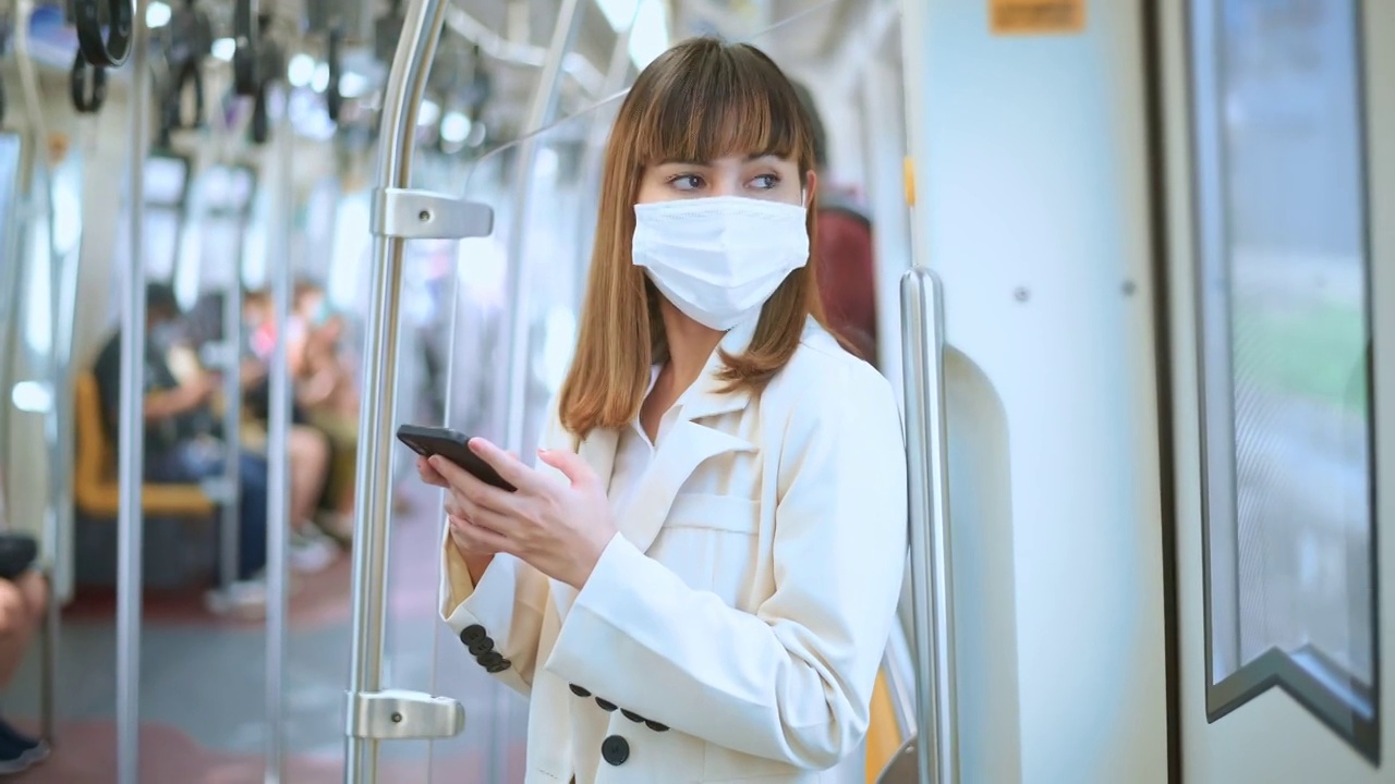 年轻女性在地铁、新冠肺炎防护、安全出行、新常态、保持社交距离、安全出行、大流行理念下佩戴防护口罩视频下载
