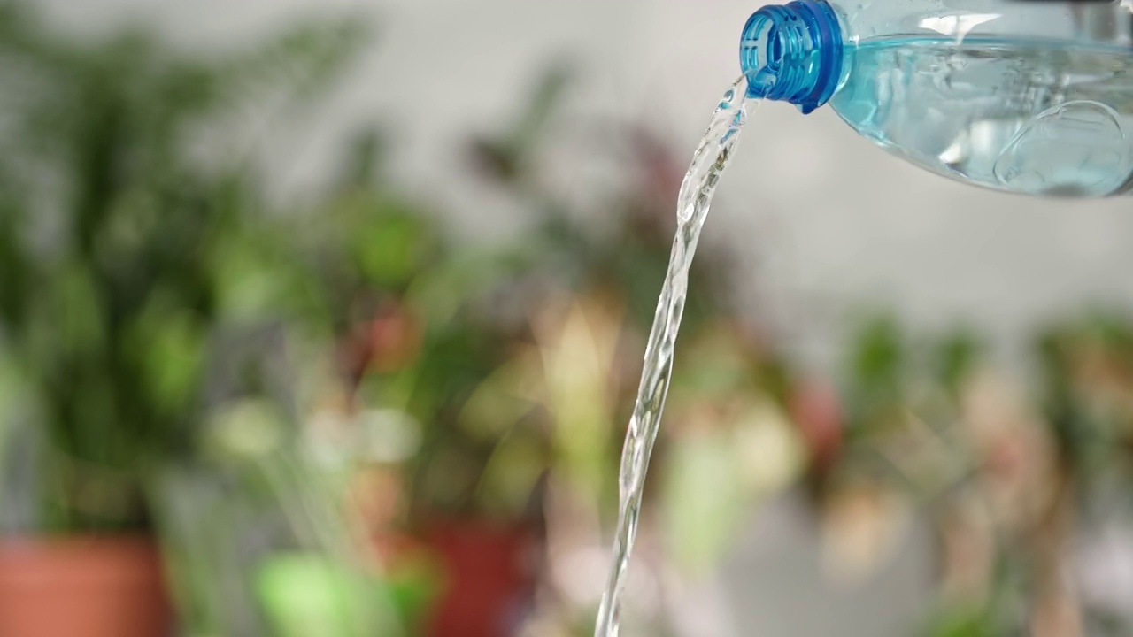 水的平衡，饮用矿泉水从塑料与透明的蓝色瓶子在绿色的背景视频素材