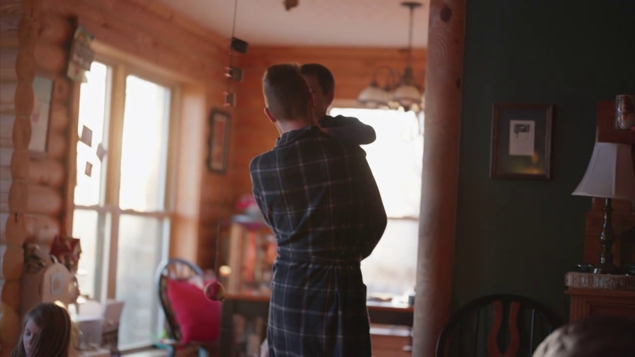 圣诞节早上，一个十几岁的男孩抱着一个残疾的小男孩视频素材