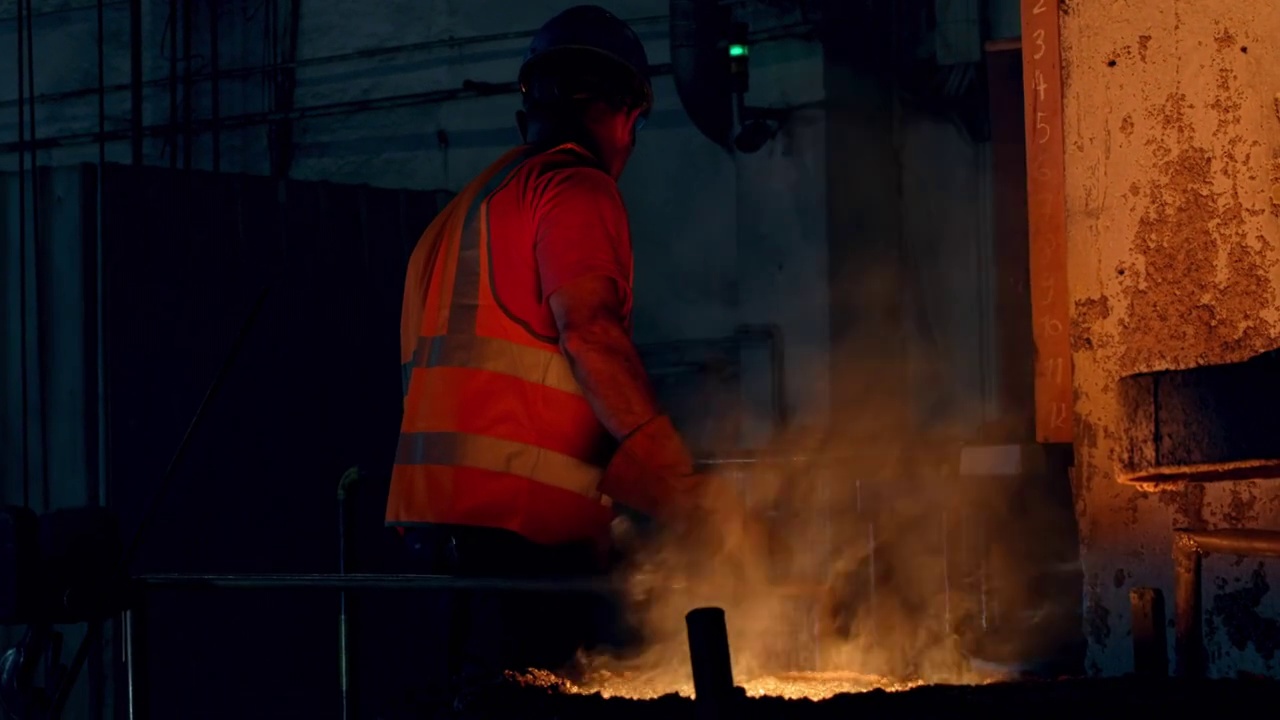 男工人从铸造厂的容器中取熔融金属样品视频素材