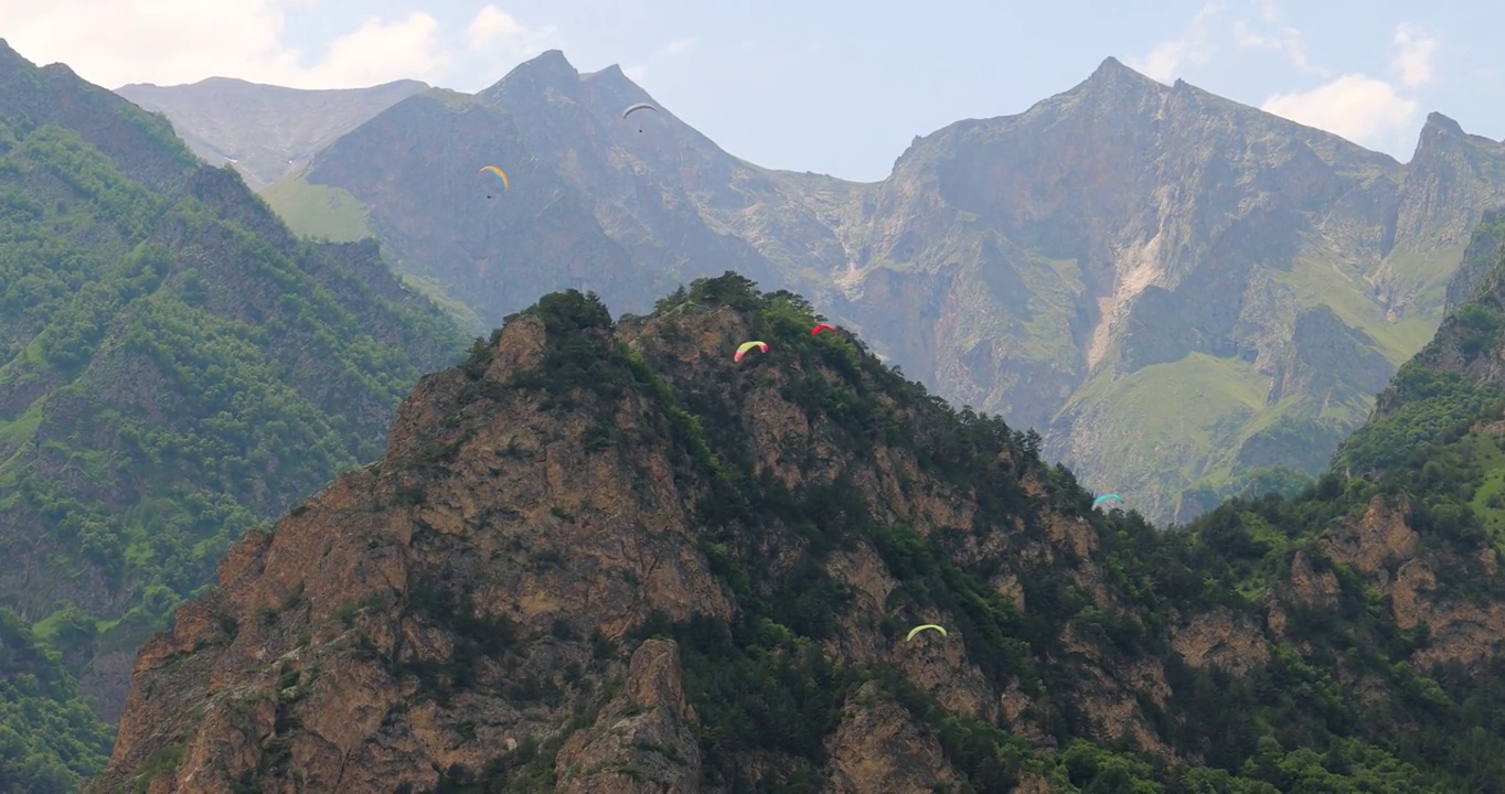 滑翔伞飞行员在云朵和青山之间飞行。视频素材