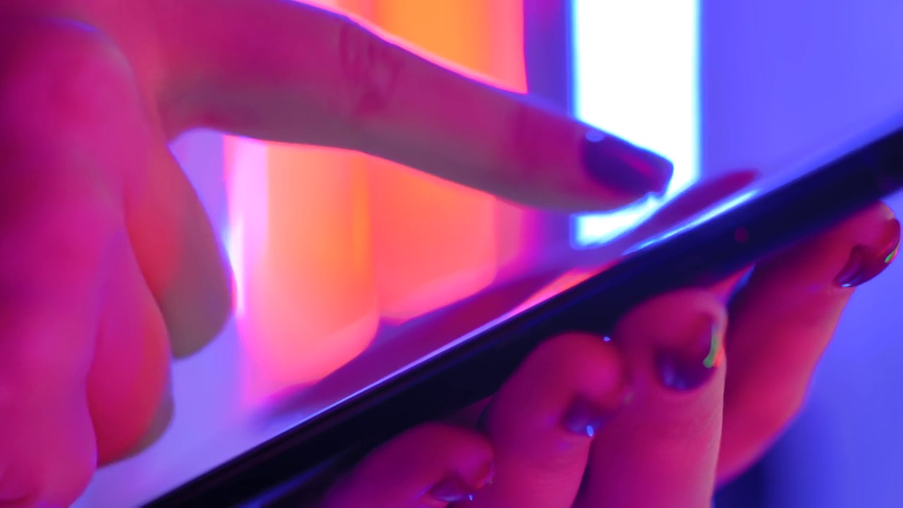 近距离观察:女人的手在明亮的彩色背景下使用智能手机视频素材