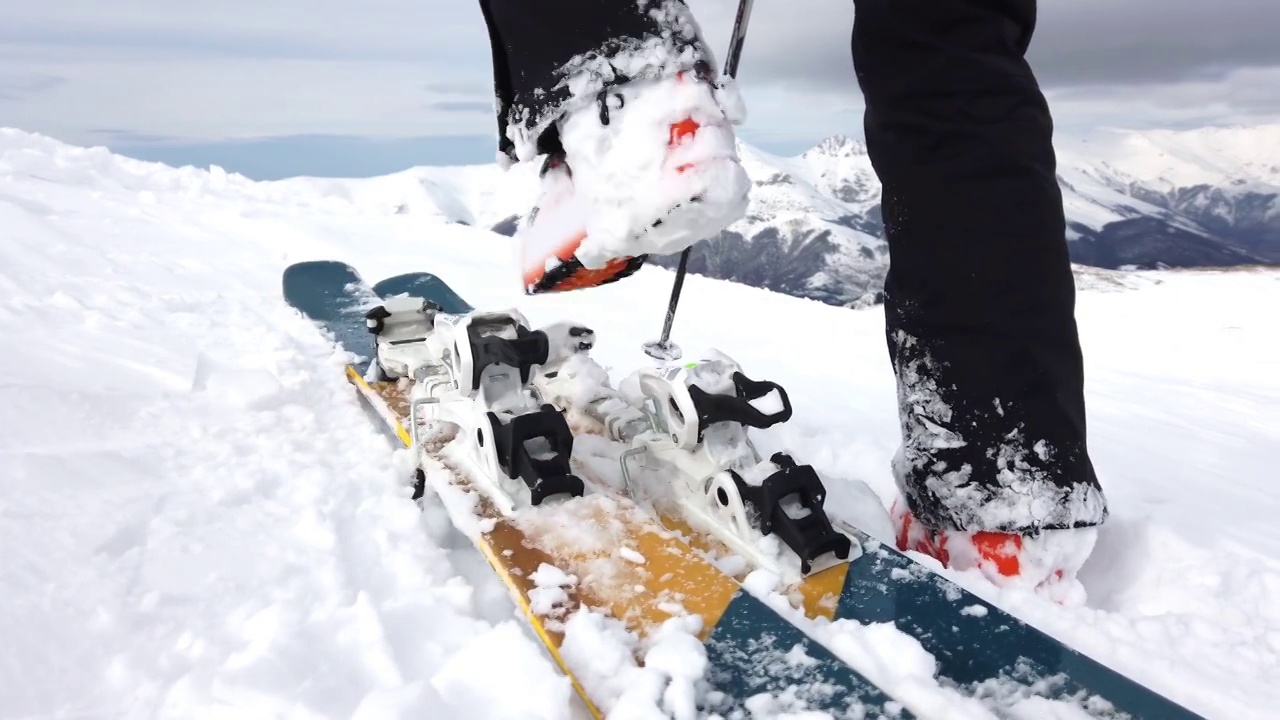 滑雪者穿上冬季滑雪板和靴子的特写，在阳光明媚的日子里滑雪板绑定概念的详细视图视频下载