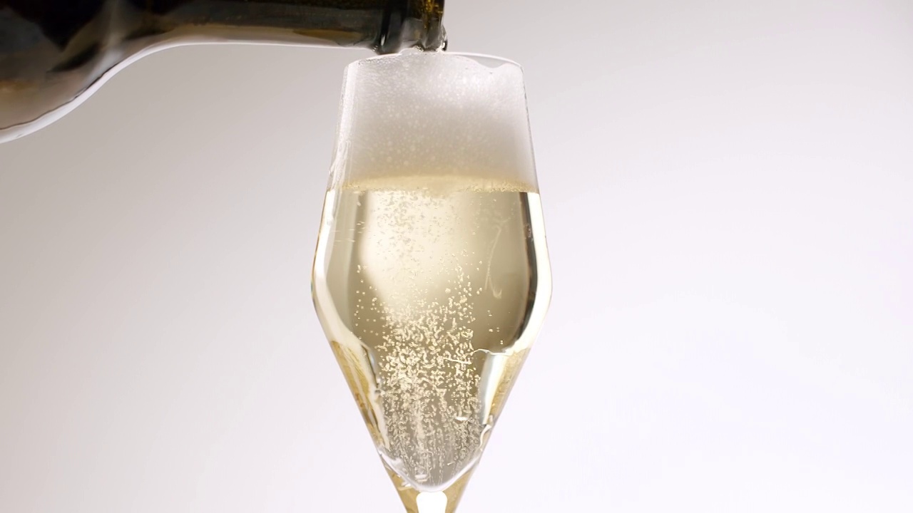 香槟酒从瓶子中倒入白色背景的漂亮玻璃杯中视频下载
