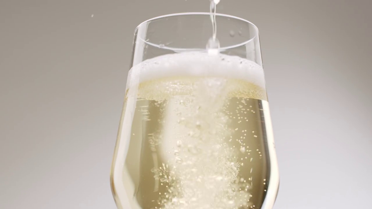 香槟酒倒进白色底色的优雅玻璃杯中视频素材