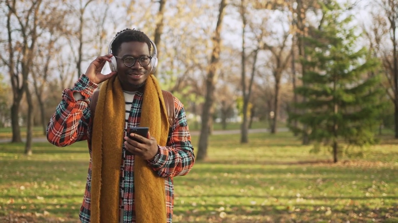 一个年轻人边跳舞边发短信，边戴着耳机在公园里听音乐视频素材