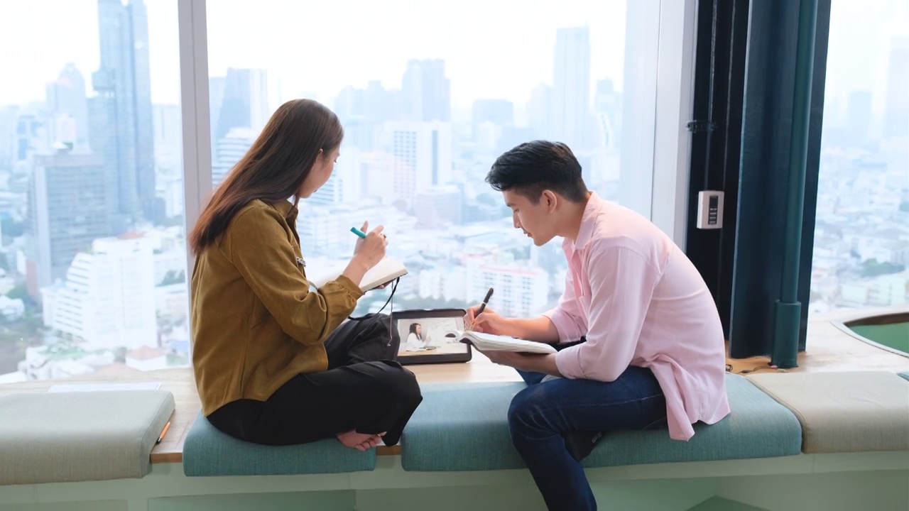 集中使用平板电脑进行在线学习的亚洲学生也会在联合办公空间的玻璃窗附近逗留视频素材