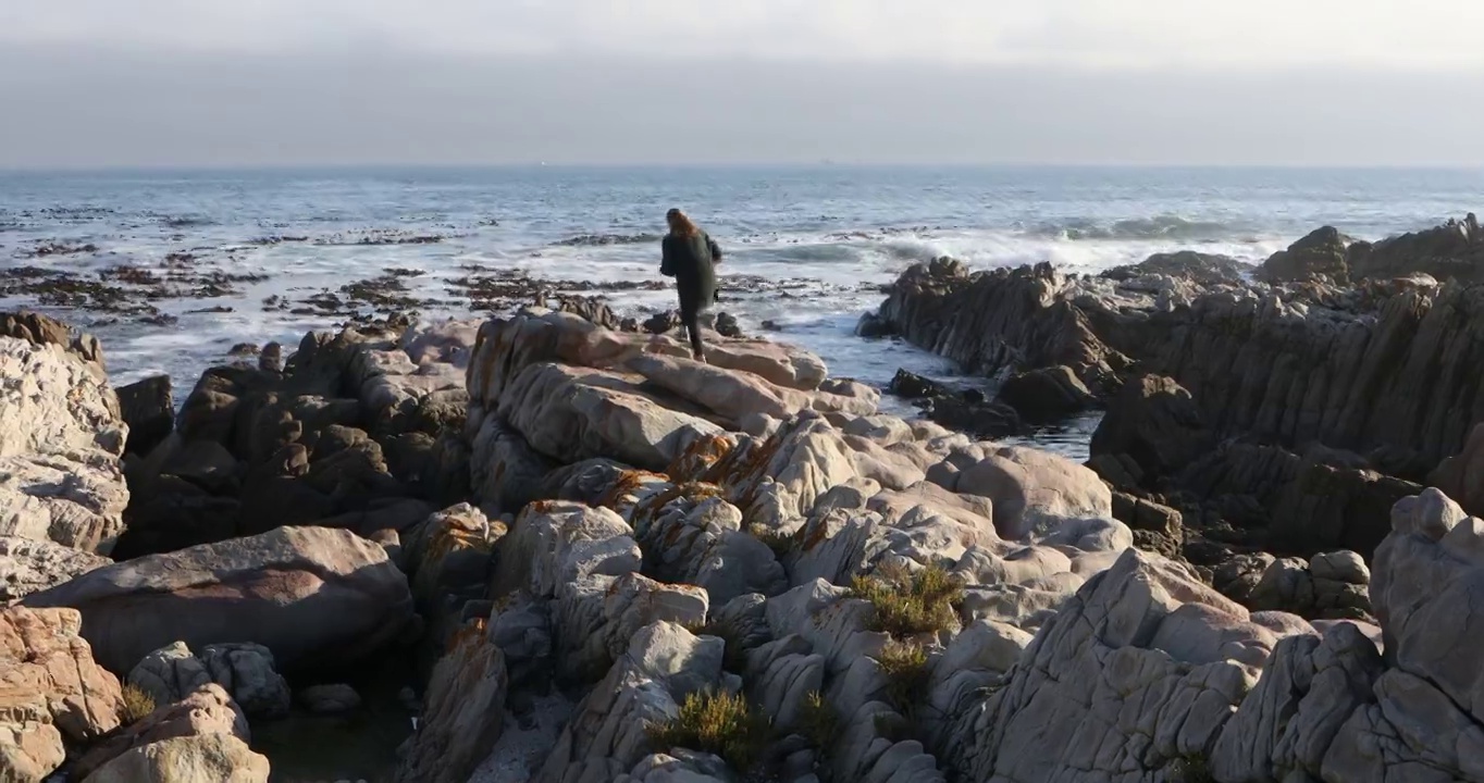 一个十几岁的女孩在南非的岩石海岸探险视频素材