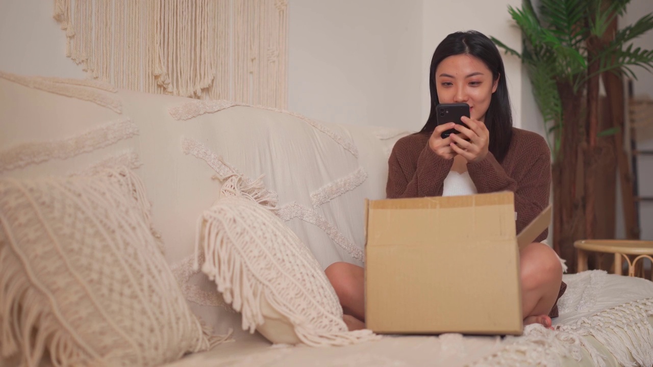 快乐的亚裔中国妇女在客厅网购时收到了破茶壶视频下载