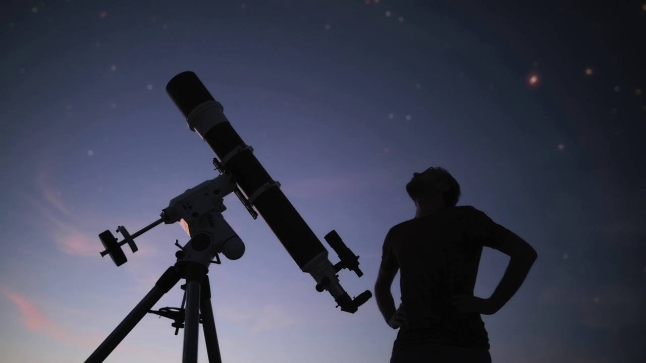 一个男人的剪影，望远镜和星空下的乡村。视频素材
