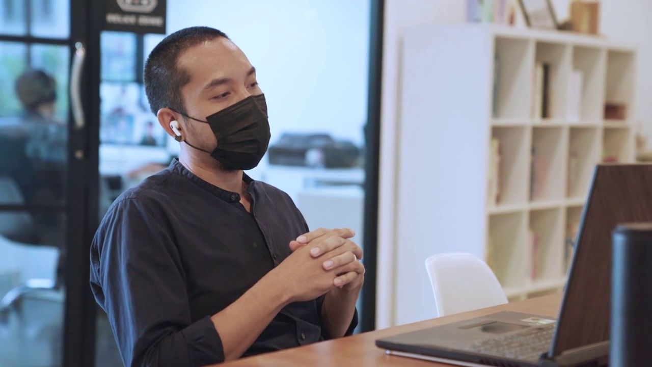 亚洲商人戴着口罩在笔记本电脑上工作视频素材