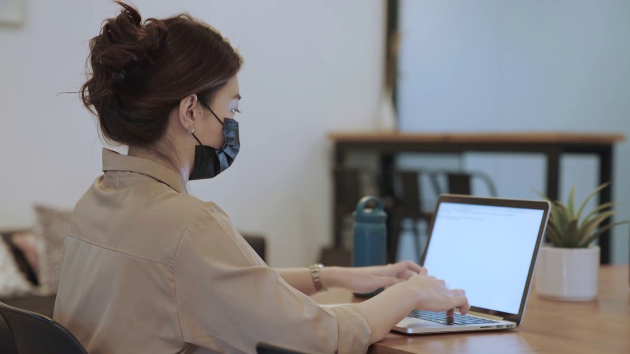 亚洲女商人戴着口罩在笔记本电脑上工作视频素材
