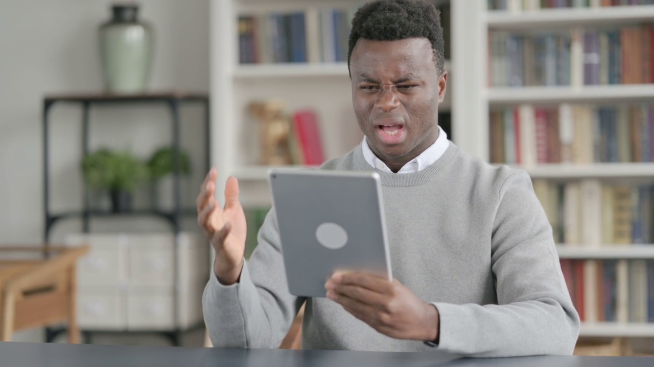 非洲人坐在图书馆里看平板电脑时的反应视频素材