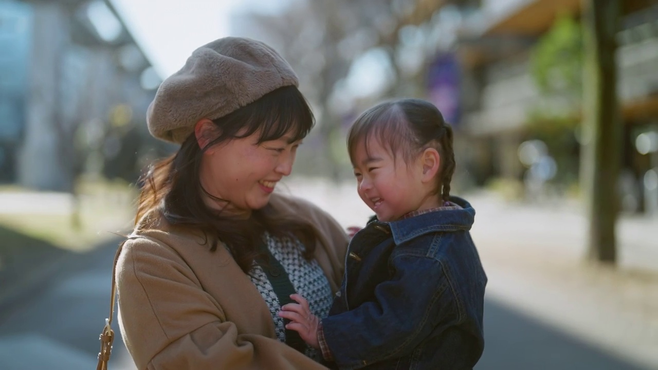 母亲和她的小女孩在城市的肖像在阳光明媚的日子在冬天视频素材