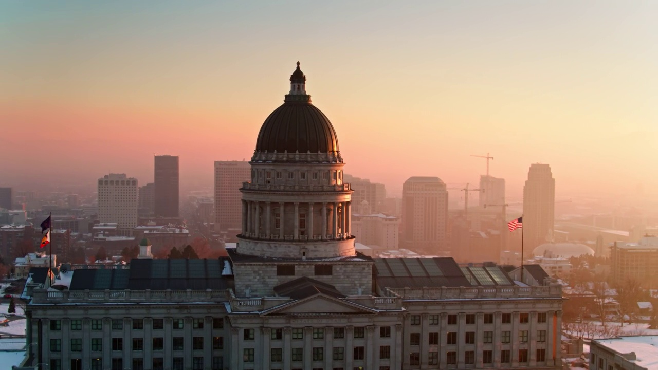 轨道无人机拍摄的犹他州国会大厦与市中心SLC建筑和戏剧性镜头耀斑从夕阳视频素材