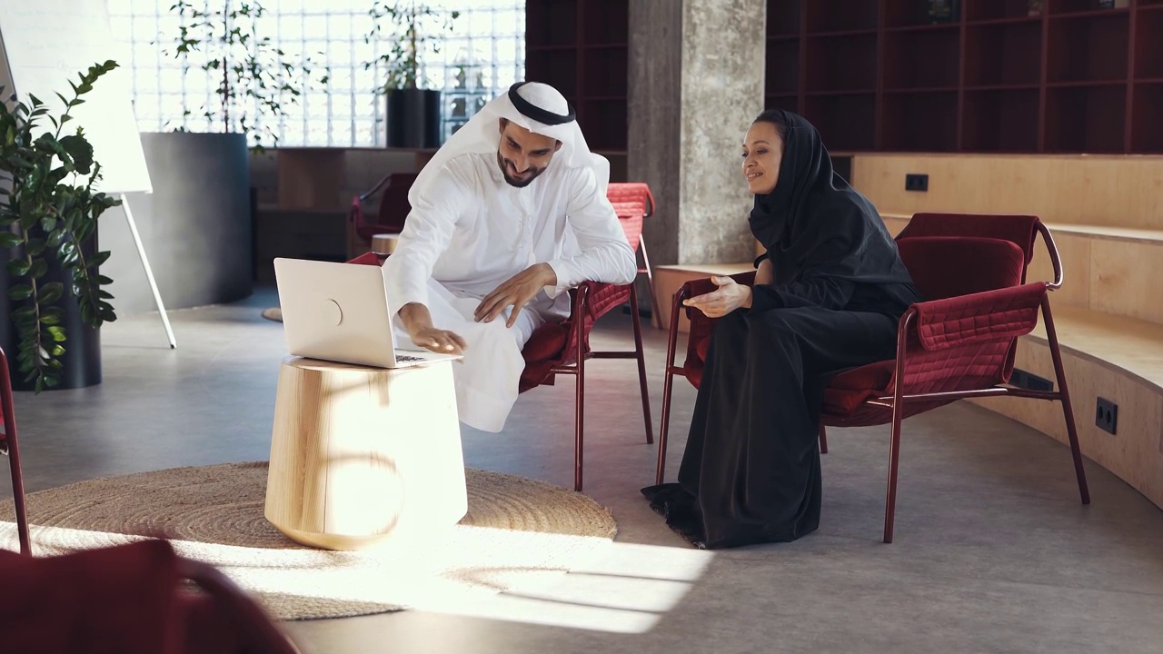 英俊的男人和女人穿着传统服装在迪拜的一个办公室工作视频素材