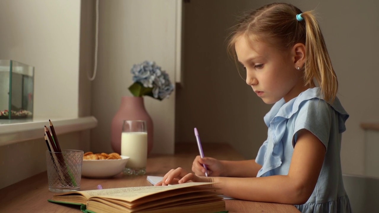 特写的侧视图集中小学女孩写笔记本与钢笔看着纸书。视频素材