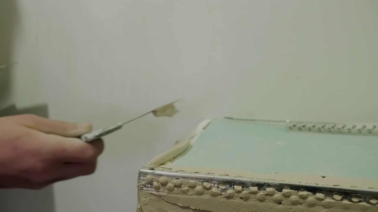 近景拍摄的手的主人用抹刀腻子墙。家里装修视频视频素材