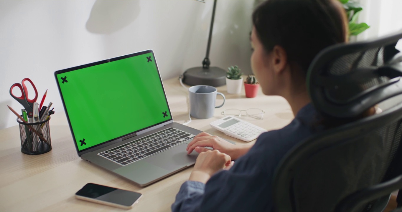 一位女士正在使用带有绿色屏幕的笔记本电脑视频素材