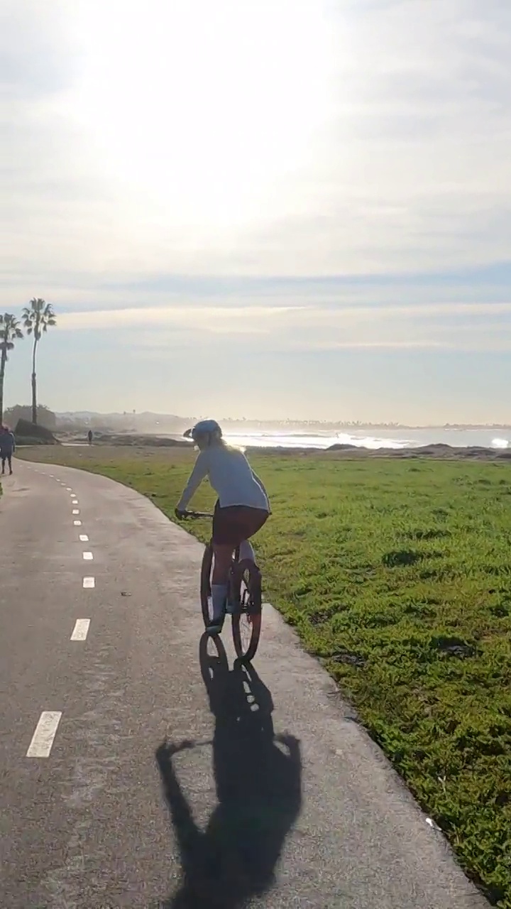 女性骑自行车者沿着海岸通道视频下载