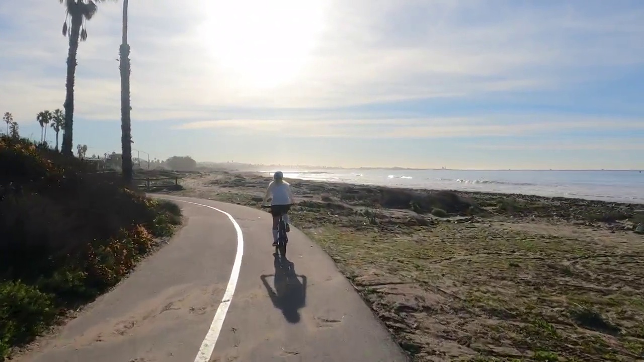 女性骑自行车者沿着海岸通道视频下载