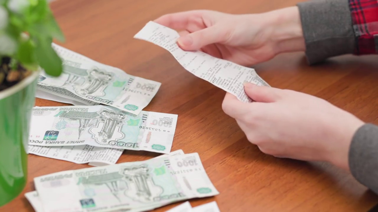 女性的手把钱放在支票旁边。关闭了。储蓄和会计视频素材
