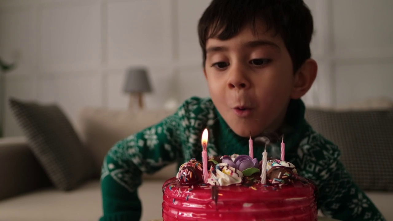 小男孩在聚会上吹熄生日蛋糕上的蜡烛。关闭了。视频素材