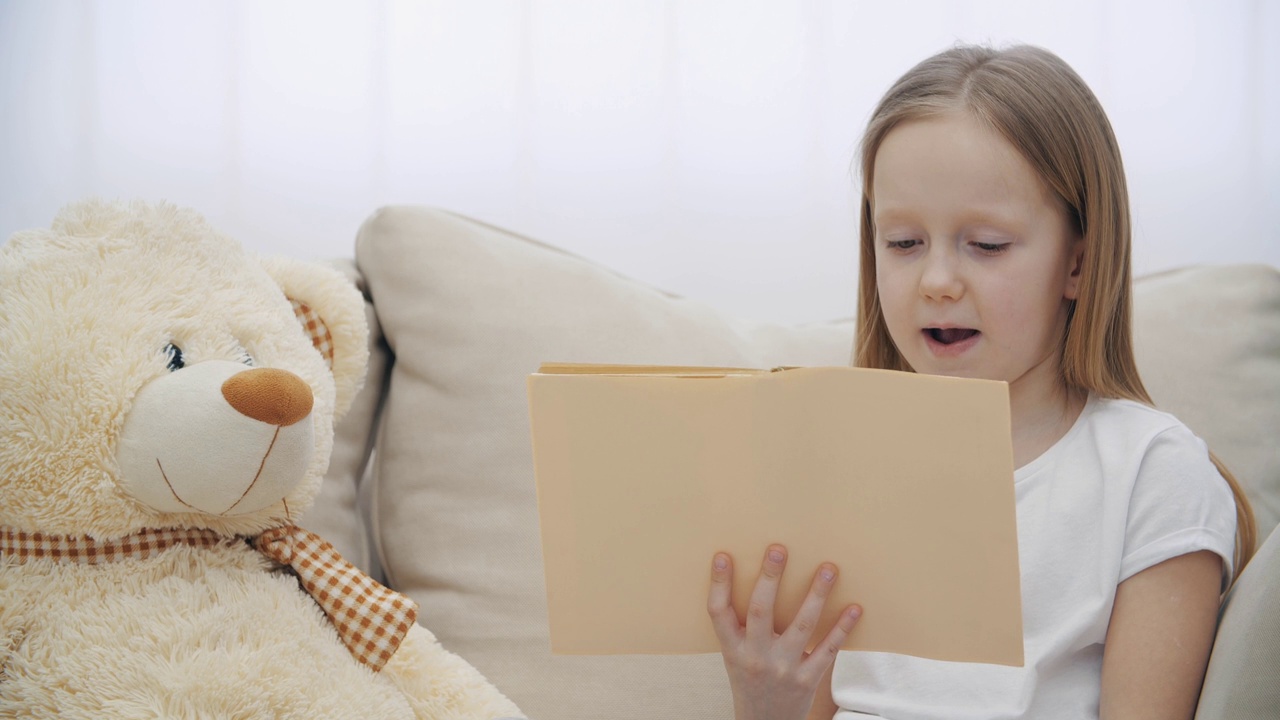 一个小女孩给她的泰迪熊读书的4k视频。视频素材