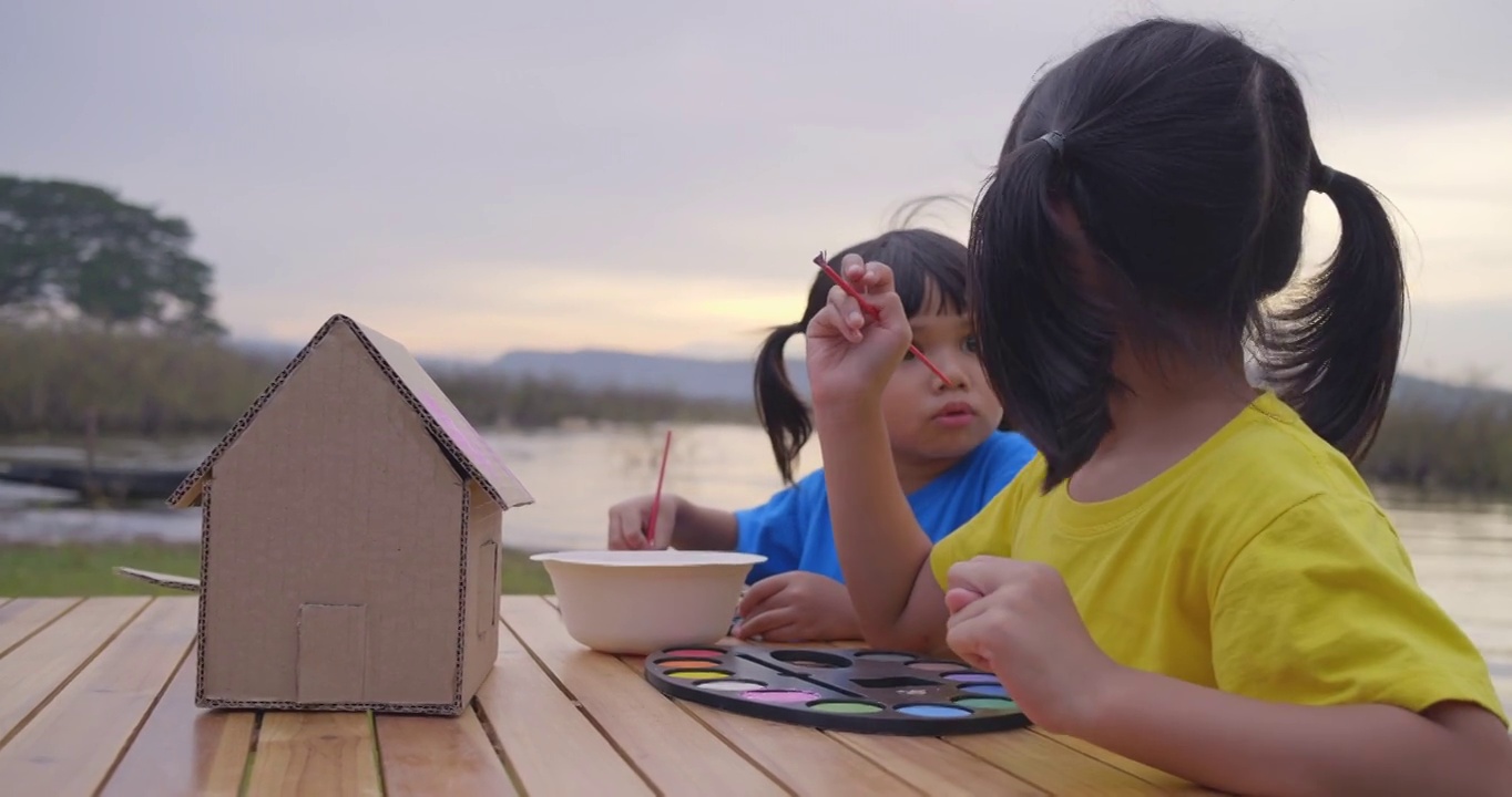 两个亚洲女孩用水画玩具模型房子。亚洲同胞们笑了，笑得很开心视频下载