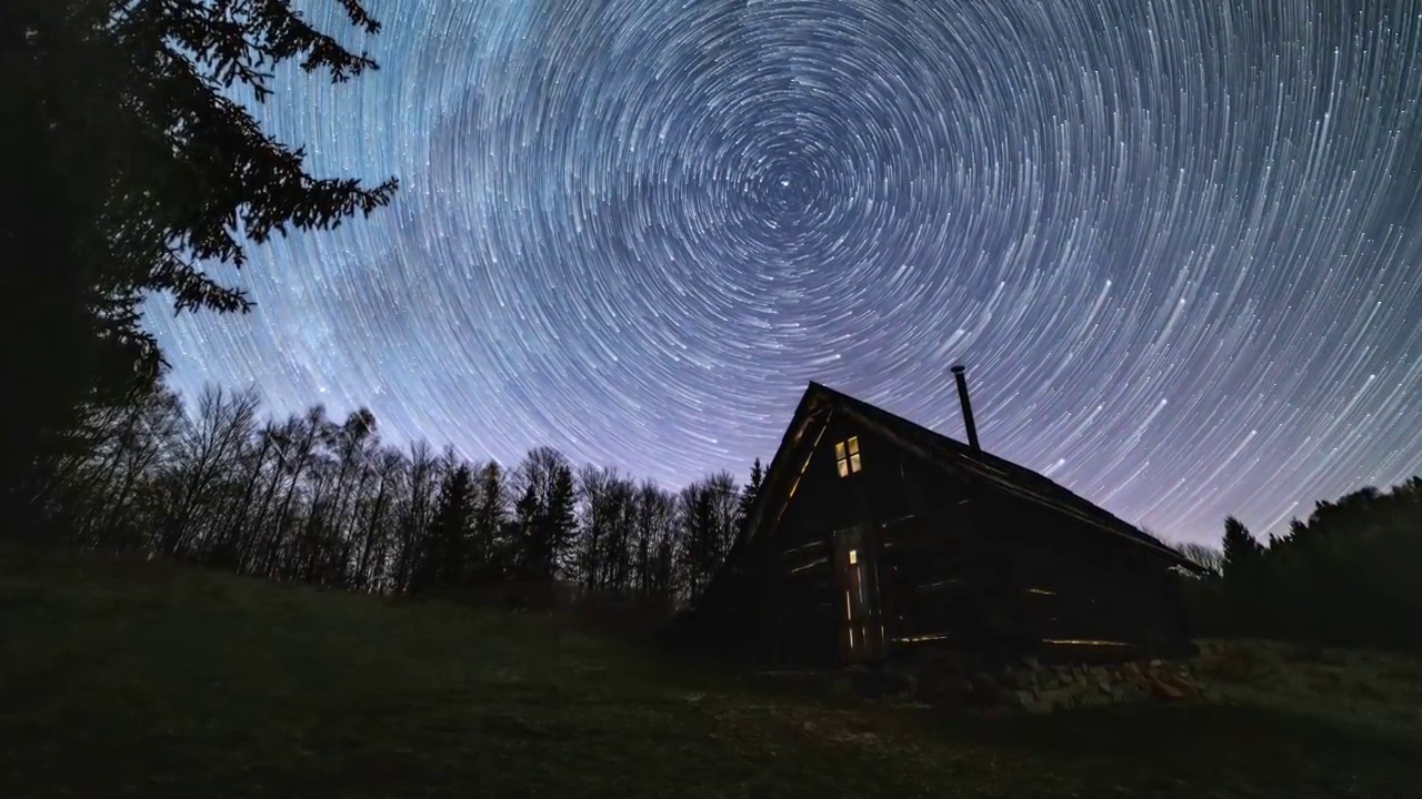 星际轨迹，银河系的恒星轨迹在夜空森林自然中古老的木屋上旋转视频下载