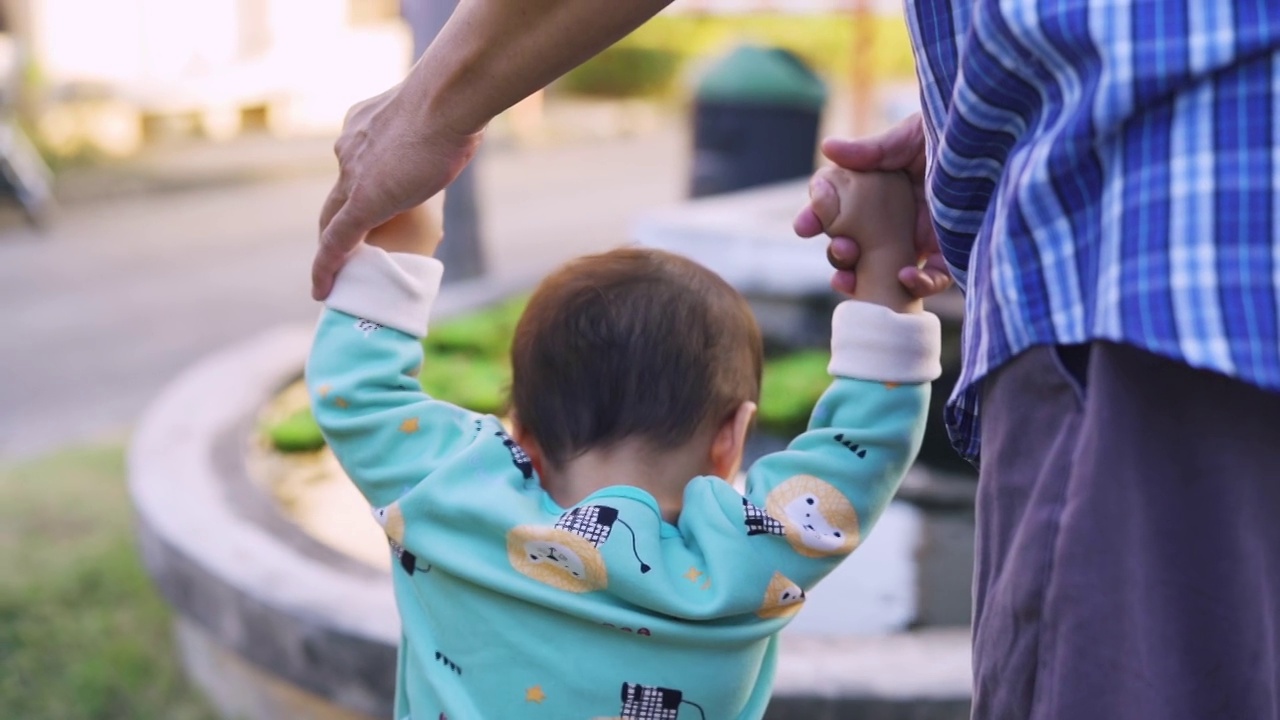 亚洲爷爷教小男孩学第一步走路。视频素材