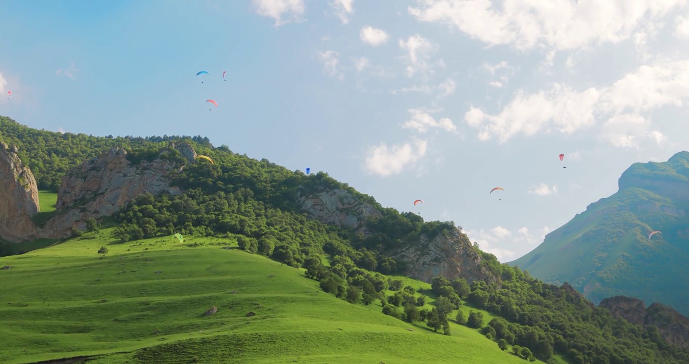 滑翔伞飞行员在云朵和青山之间飞行。视频素材