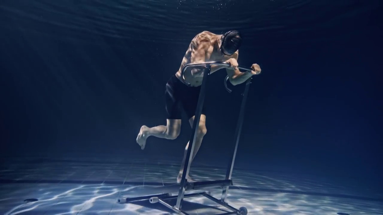 电影镜头，肌肉发达的年轻男性运动员在水下固定的跑步机上努力和决心锻炼。运动、健身、健康生活方式、娱乐的概念视频下载