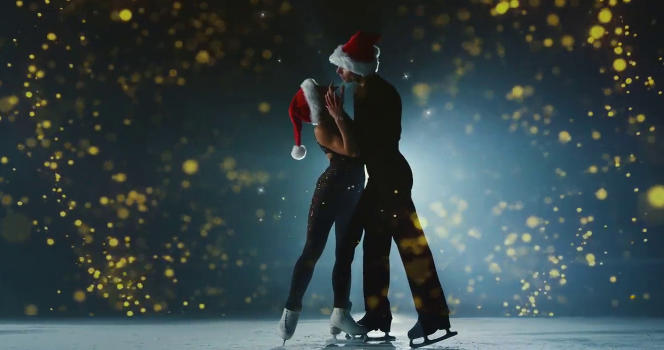 电影拍摄的一对花样滑冰选手戴着圣诞帽表演一对花样滑冰舞蹈与魔术发光在冰场在圣诞节比赛。假期和魔术的概念视频下载