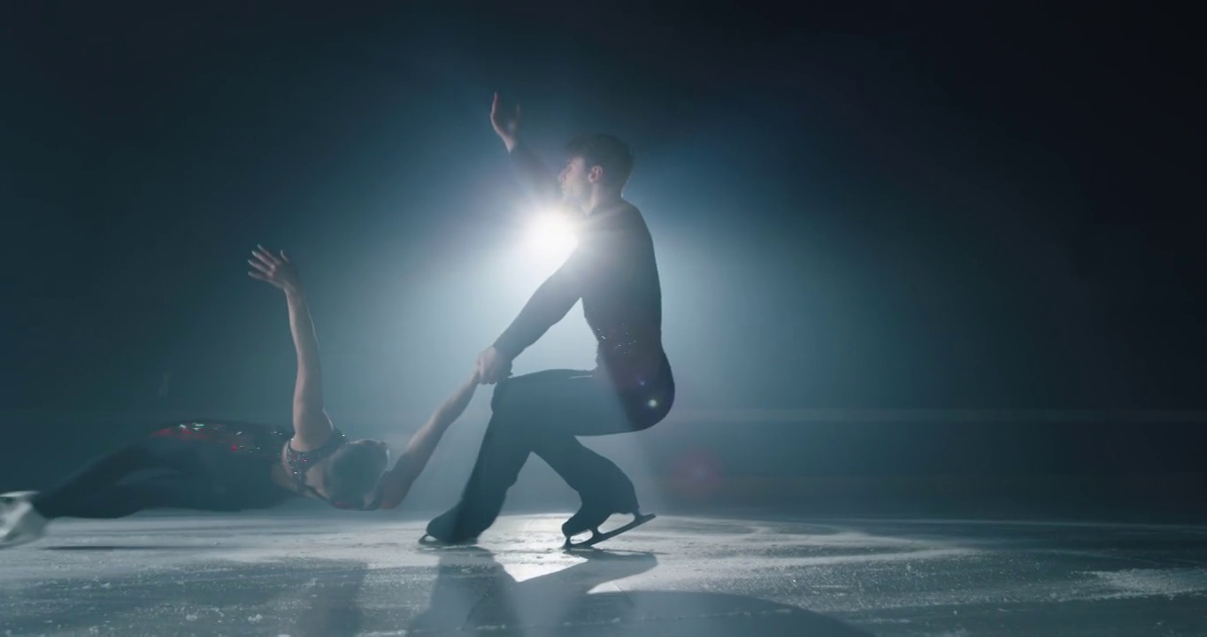 在比赛开始前，一对年轻的花样滑冰艺术夫妇正在冰场上表演双人花样滑冰的舞蹈。完美，精确，自由，激情的理念。视频素材